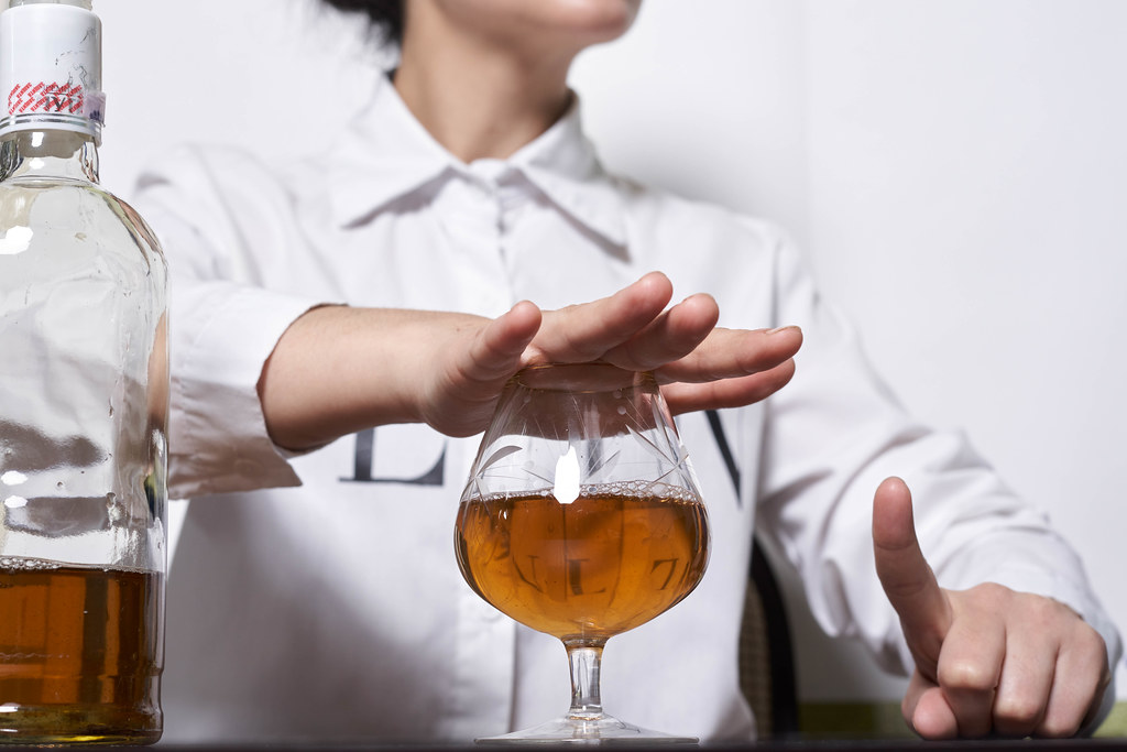 woman with her hand over glass of alcohol saying no